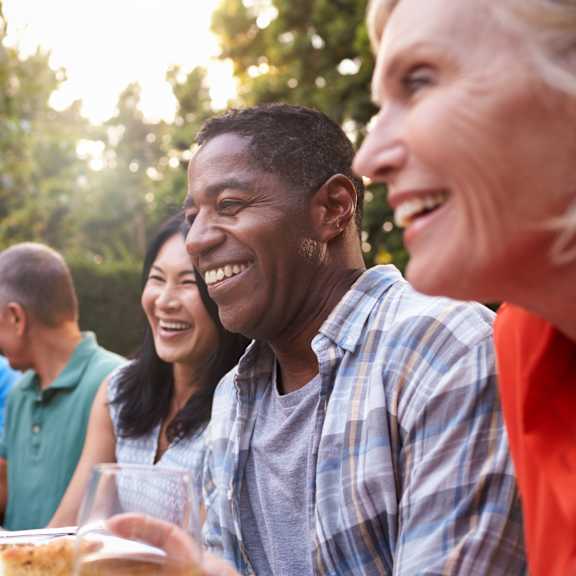 a group of people sitting around a table talking and eating food