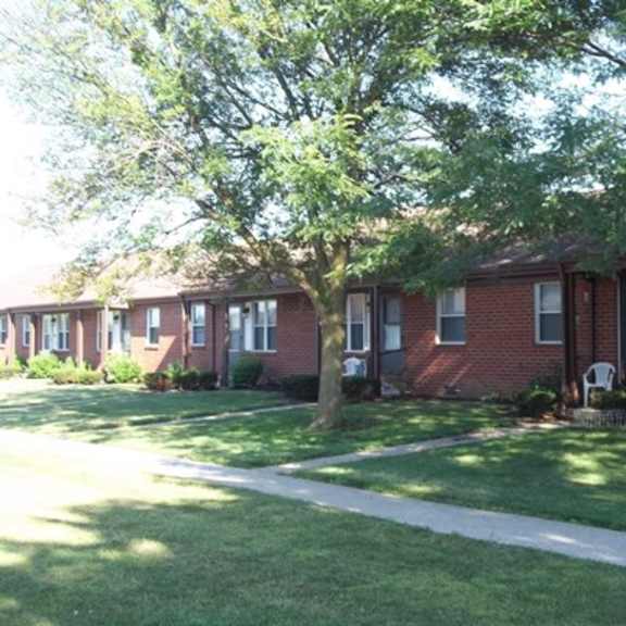 a red brick house with a sidewalk in front of it