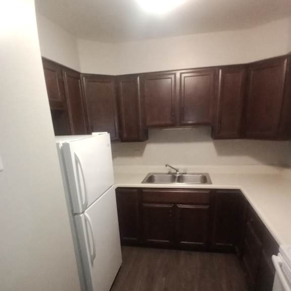 an empty kitchen with a refrigerator and a sink