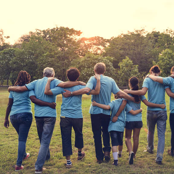 a group of people wearing blue shirts walking in a park