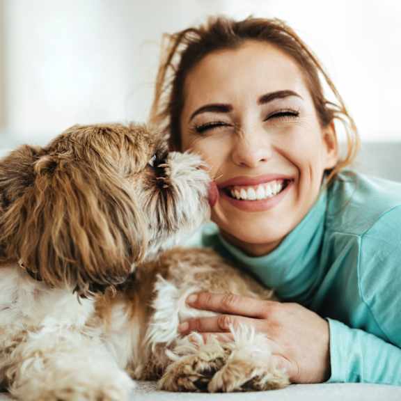 a woman is hugging a small, fluffy dog.