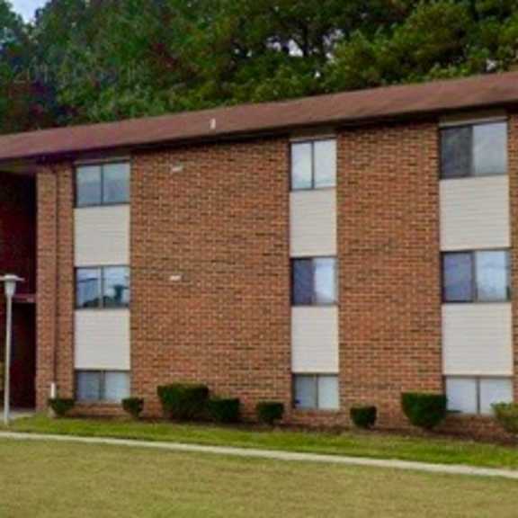 a large brick building with a grassy area in front of it