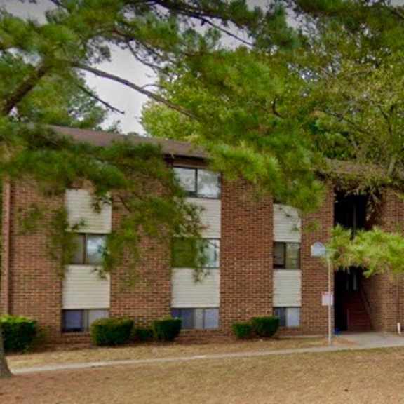 a brick apartment building with trees in front of it