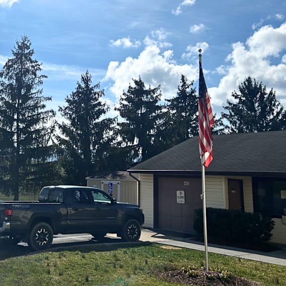 a truck parked in front of a house with an flag