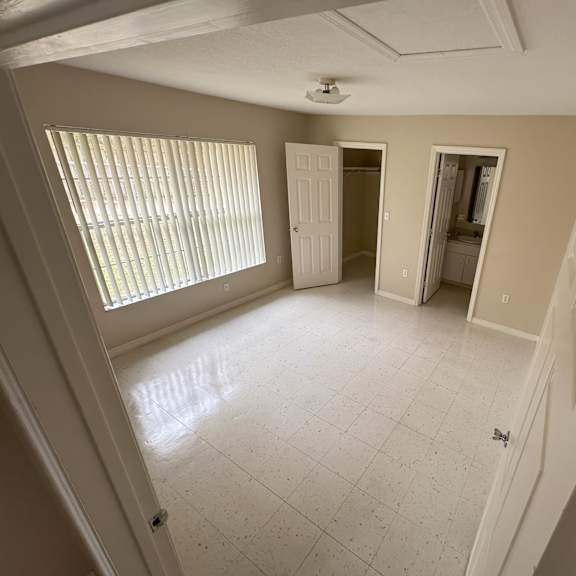 a room with a white tile floor and a window with blinds.
