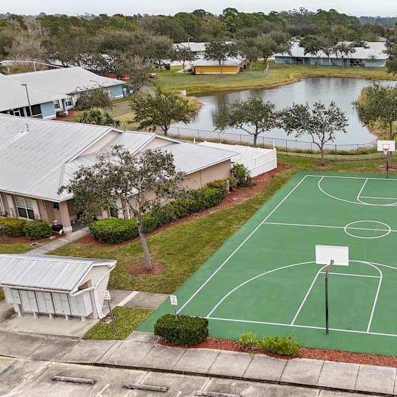 a basketball court is surrounded by trees and a lake.