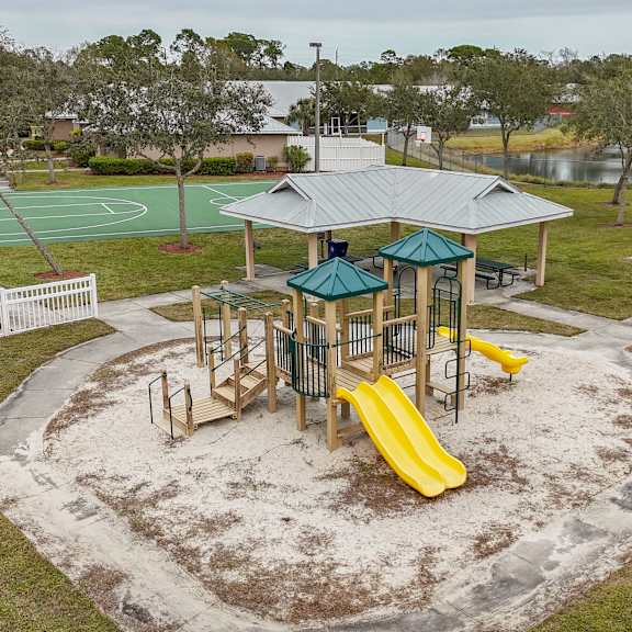 a playground with a yellow slide and a green roofed pavilion.