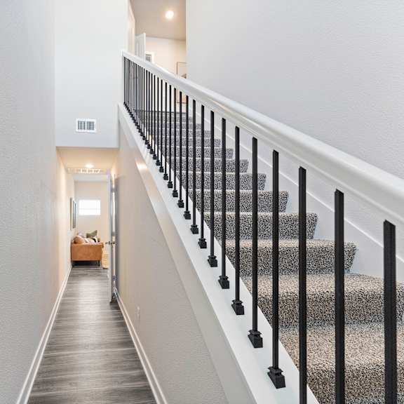 Thumbnail 8 of 24 A staircase with a black railing and a grey carpeted runner.