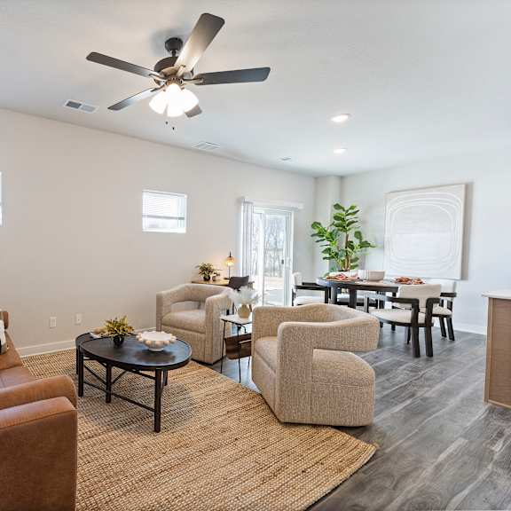 Thumbnail 3 of 24 A living room with a brown couch and a ceiling fan.