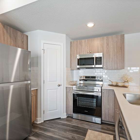 Thumbnail 9 of 24 A modern kitchen with a stainless steel refrigerator and a built-in oven.
