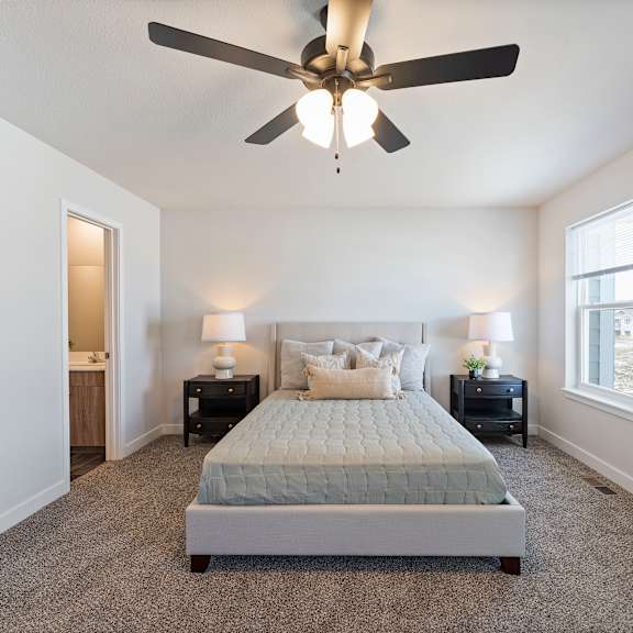 Thumbnail 22 of 24 A bedroom with a bed, two nightstands, and a ceiling fan.