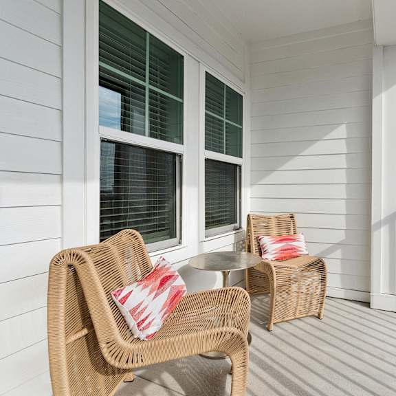 A balcony with two chairs and a table.
