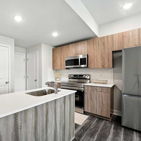 Thumbnail 5 of 23 A modern kitchen with a white countertop and stainless steel appliances.