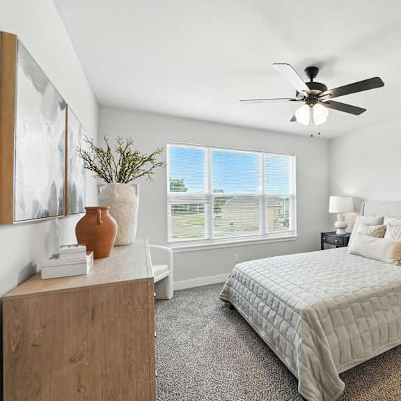 Thumbnail 15 of 23 A bedroom with a bed, nightstand, and a ceiling fan.