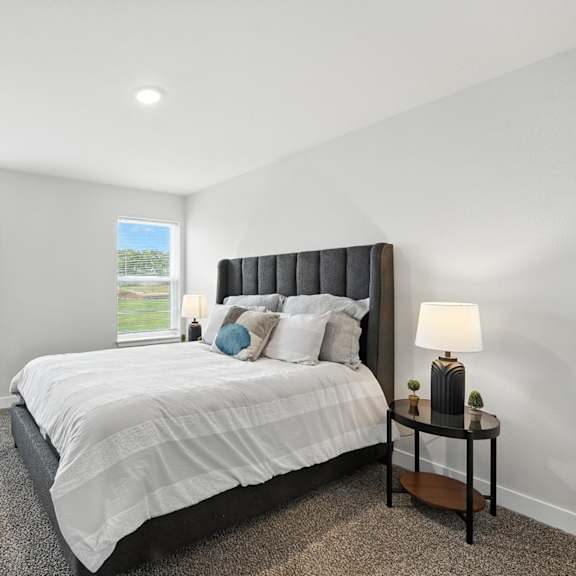 Thumbnail 13 of 23 A bedroom with a large bed and a window overlooking a green field.
