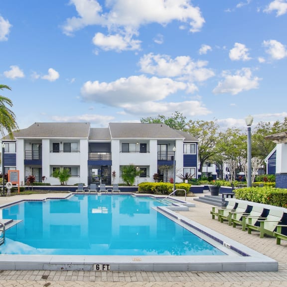 a swimming pool in front of a building with palm trees