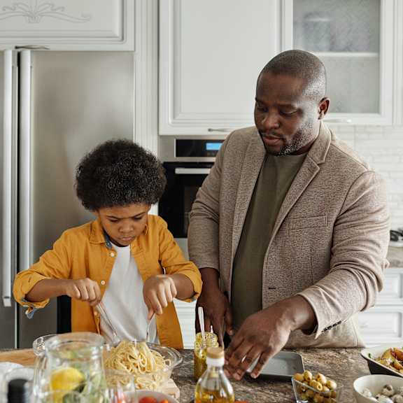 Three people are preparing food in a kitchen.