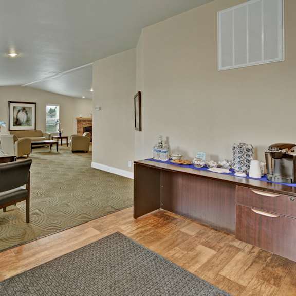 welcoming, functional community space here at four seasons featuring a business center with desks and chairs, an open lounge area with comfortable seating, and a refreshment station with coffee and snacks. neutral carpeting, wood-style flooring, and ample lighting create a convenient shared space for work and relaxation.