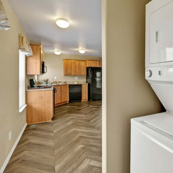 convenient, in-home laundry area here at four seasons featuring a stacked washer and dryer tucked into a dedicated alcove just off the kitchen. neutral walls and easy-access placement make everyday laundry simple while keeping the main living space organized and uncluttered.
