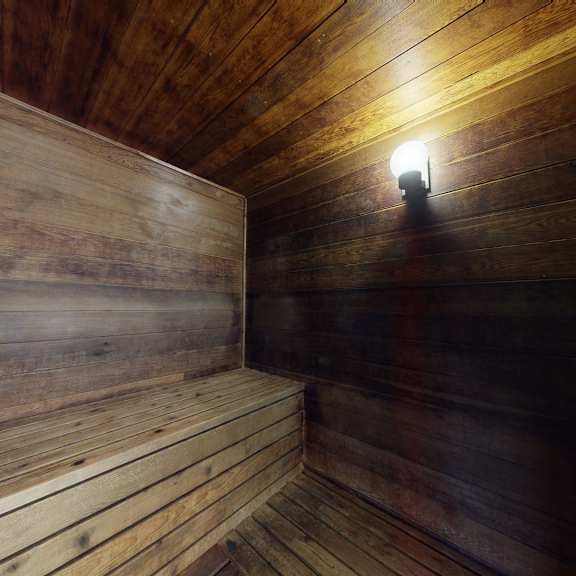 wood-paneled sauna interior here at the club at eagle pointe apartments with soft amber lighting, highlighting a warm, rustic bench along the left wall. cozy, inviting atmosphere.