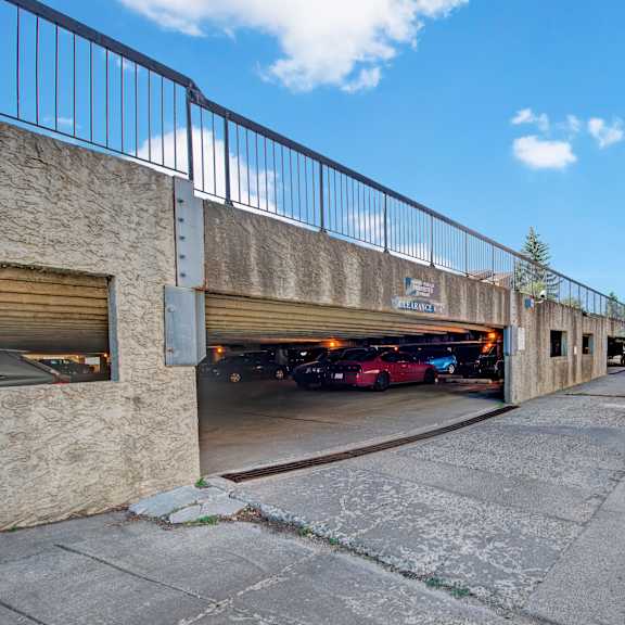 a convenient covered parking garage here at gateway square with clearly marked spaces, easy drive-in access, and open surroundings under a bright blue sky.