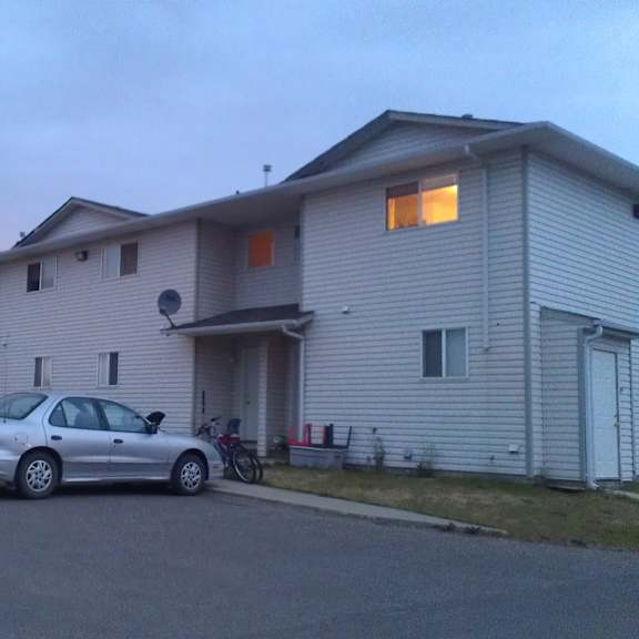 a peaceful exterior view here at willowview terrace showing a row of townhome-style buildings with light siding and convenient parking right out front. a soft evening sky and warm window lighting add a calm, welcoming feel to the community.