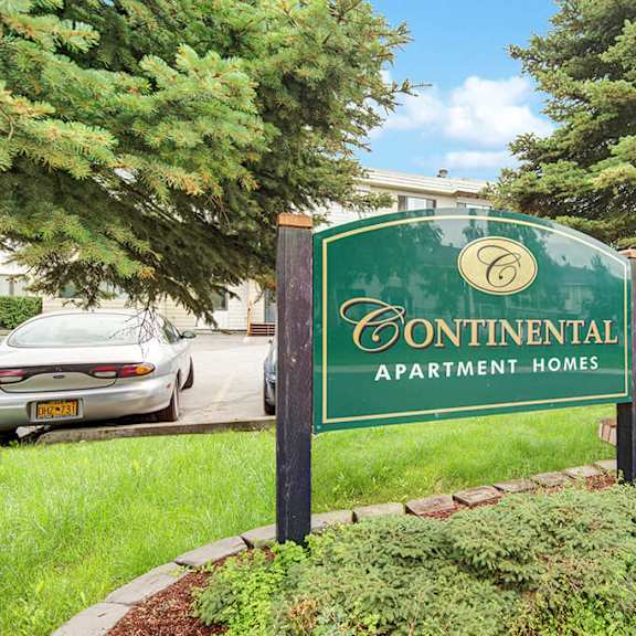sign for "continental apartment homes" in a landscaped area with evergreen trees. parked cars are visible in the background under a clear sky.