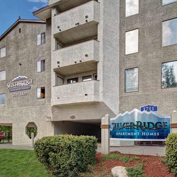 exterior of silver ridge apartment homes, featuring textured gray walls, multiple balconies, and a prominent blue sign with the address number 1711.