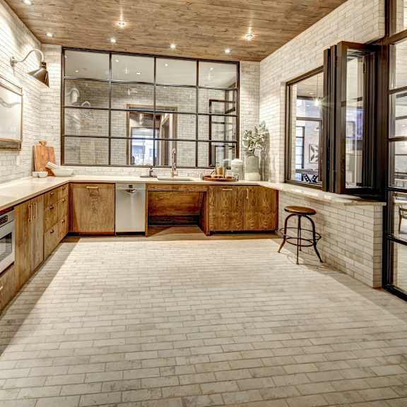 a kitchen with a white brick wall and wooden cabinets.