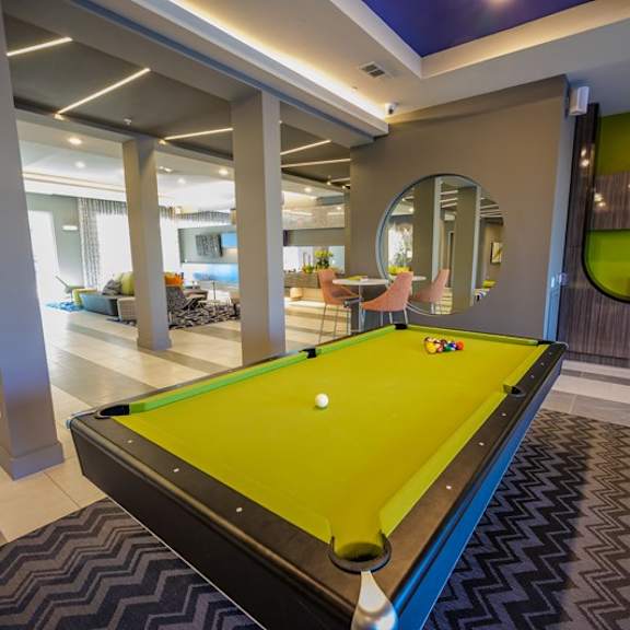 a stylish community lounge here at harmony luxury with a pool table, modern seating areas, sleek design accents, and ambient lighting, creating a relaxed and inviting space for socializing and entertainment.