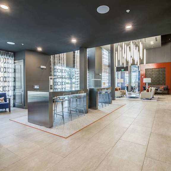 a contemporary community lounge here at harmony luxury with high-top seating, sleek tables, plush seating areas, and statement pendant lighting, complemented by tall windows, modern finishes, and an open layout that creates a polished, welcoming atmosphere.