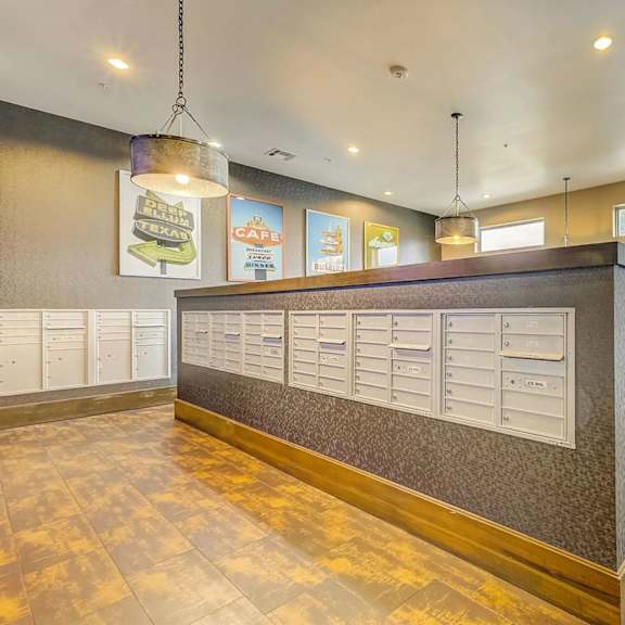 a mailroom here at skyline farmers market with central parcel counter, white mailbox panels, warm wood-look floors, pendant lights, and colorful café-style wall posters.