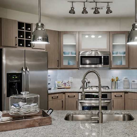 a kitchen here at skyline farmers market with light wood cabinets, stainless appliances, granite island, deep sink, and standout chrome pendant lights over the counter.