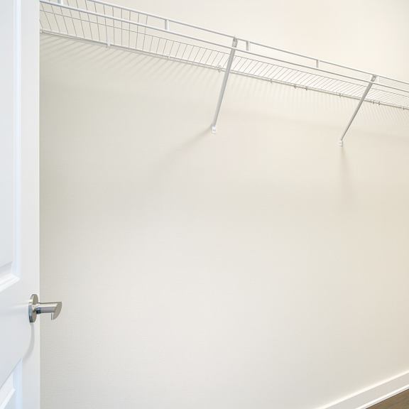 a large walk-in closet with a white door and a white shelves.