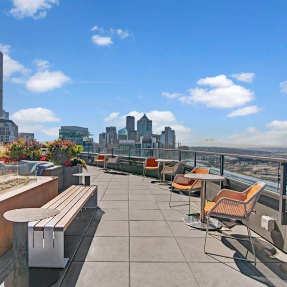 a rooftop patio with chairs and a view of the city.