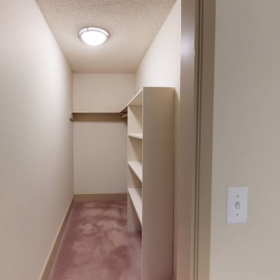 a spacious walk-in closet here at whispering cedars with soft carpet, built-in shelving, and a hanging rod, offering ample storage space and an organized layout for comfortable, convenient living.
