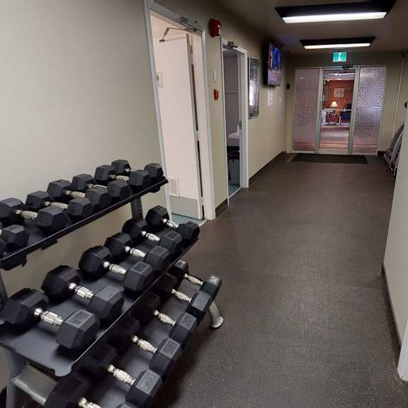 hallway in a fitness center here at cambridge west apartment homes with a rack of black dumbbells on the left. a door labeled "authorized personnel only" is on the right, leading to a lit room.