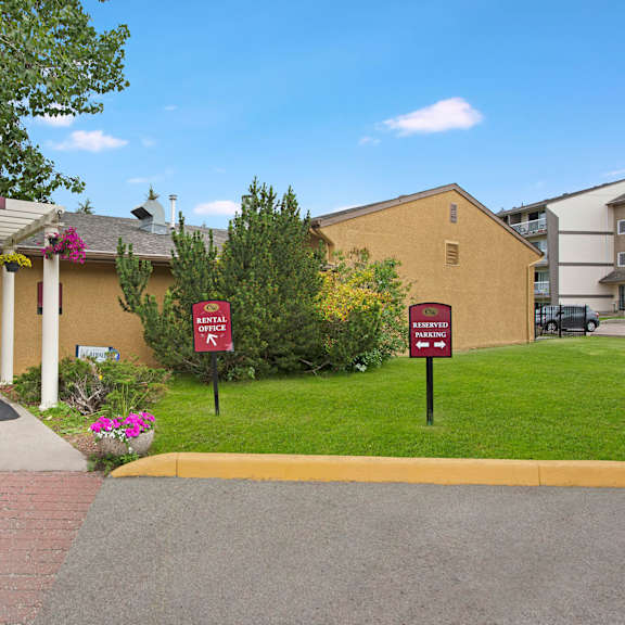 entrance to cambridge west apartment homes leasing office with a sign reading "welcome home" under a pergola adorned with hanging flowers. nearby, signs indicate rental office and parking.