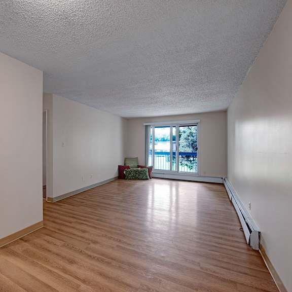 empty apartment here at gateway gardens apartment homes with wood flooring, an open kitchen with wooden cabinets, and bright natural light from large windows. serenity, simplicity, and modernity.