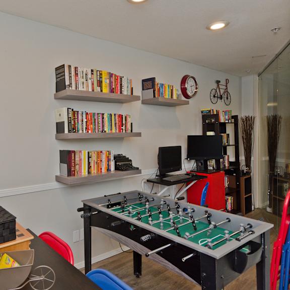 office break room here at somerset pointe apartment homes with colorful chairs, foosball table, bookshelves filled with books, a computer desk, and playful wall decor creating a fun vibe.