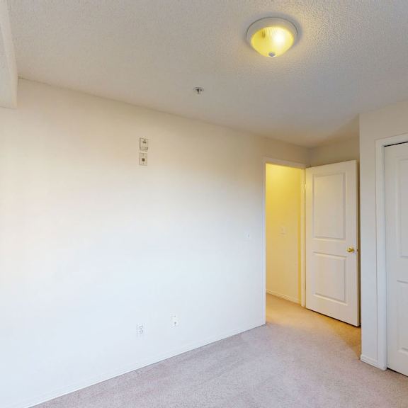 empty room here at somerset pointe apartment homes with beige carpet, white walls, and a ceiling light. an open door leads to a hallway, and a large closet with double doors is on the right. neutral and clean ambiance.