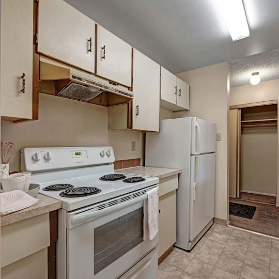 small, neutral-toned kitchen here at sterling place apartment homes with white cabinets, electric stove, and refrigerator. bright lighting and a narrow layout create a cozy atmosphere.