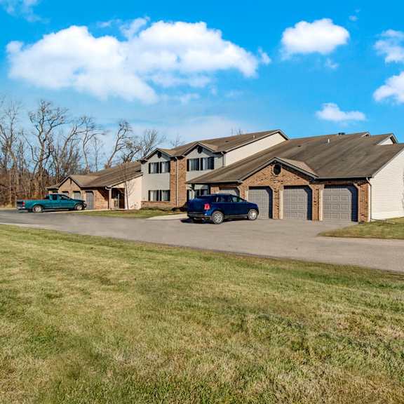 a welcoming exterior here at river’s cove featuring attached garages, open green space, and a well-maintained setting, creating a quiet, spacious, and inviting community atmosphere.