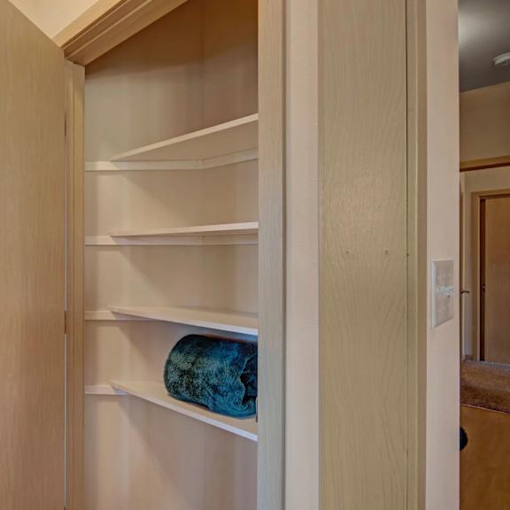 a practical storage closet here at vue at pinnacle park with built-in corner shelving, multiple tiers for organization, and easy hallway access for convenient everyday storage.