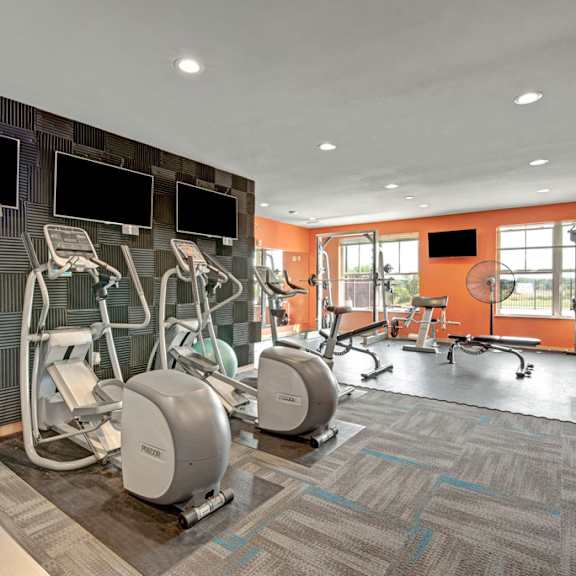a modern fitness center here at vue at pinnacle park with cardio machines, ellipticals, free weights, strength equipment, wall-mounted tvs, and bright windows for an energizing, well-equipped workout space.