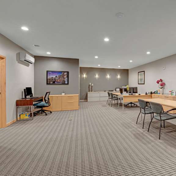 a spacious business center here at vue at pinnacle park with multiple workstations, desks and chairs, computer setups, bright recessed lighting, and a quiet, professional layout for comfortable remote work and study.