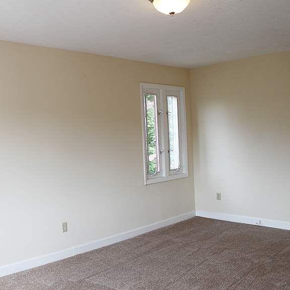 a room with a carpeted floor and two windows.