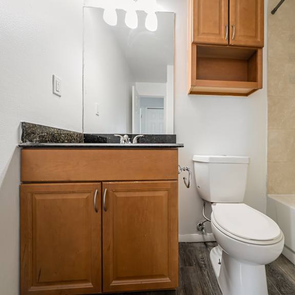 updated bathroom with wood cabinetry, black marble countertops, and stone wall tiles