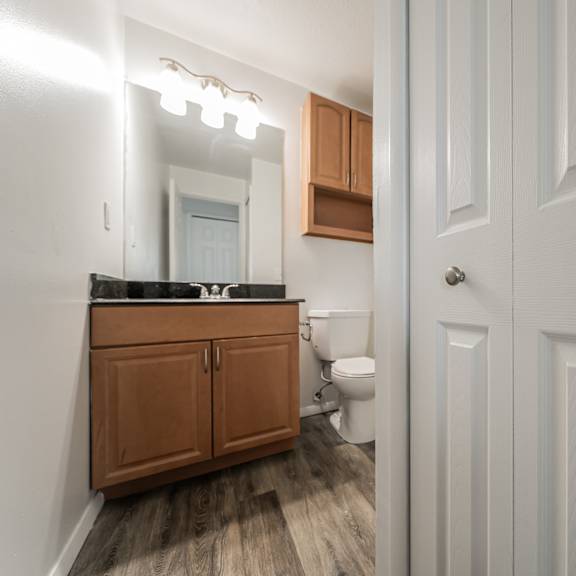 bathroom with wood cabinets, black marble counters, and linen closet