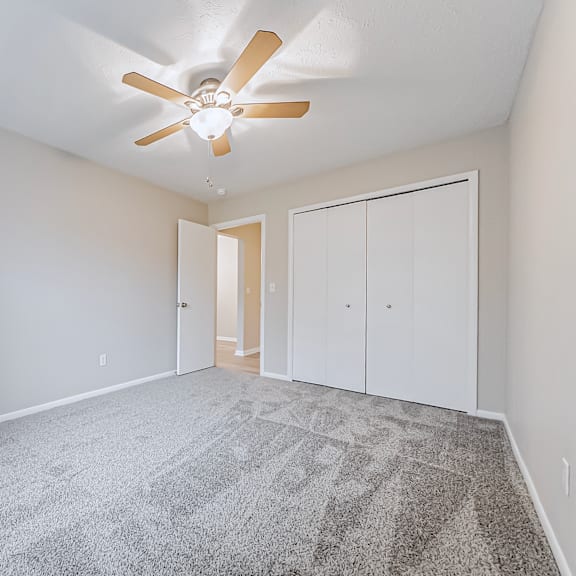 a room with a ceiling fan and carpeted floor.